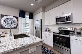 A modern kitchen with granite countertops and stainless steel appliances.