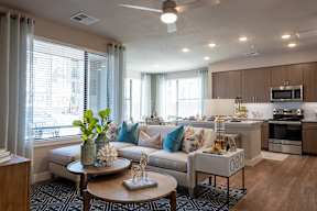 A modern living room with a sofa, coffee table, and kitchen area.