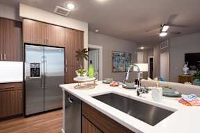 A modern kitchen with a stainless steel refrigerator and wooden cabinets.