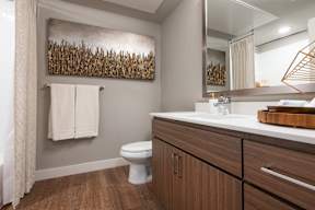 A bathroom with a toilet, sink, and a wooden wall art.