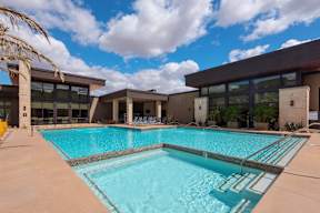 A large swimming pool in front of a building with a cloudy sky in the background.