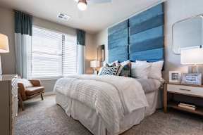 A bedroom with a large bed and a chair.