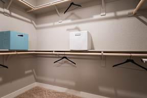 A white box is on a shelf with a blue box and three hangers.