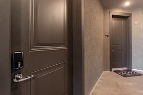 A hallway with a door and a wall-mounted device on the wall.