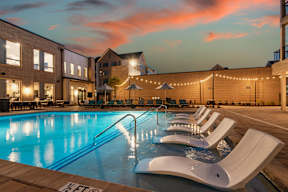 A pool with lounge chairs and string lights.