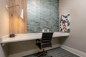 A room with a desk, chair, and a painting on the wall.