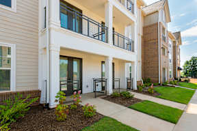 A modern apartment building with a well-maintained front yard.