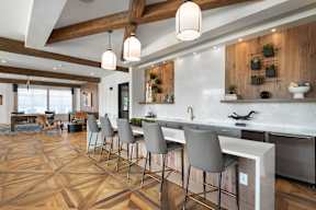 A kitchen with a white counter top and grey chairs.