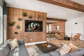 A living room with a grey couch and a wooden wall.