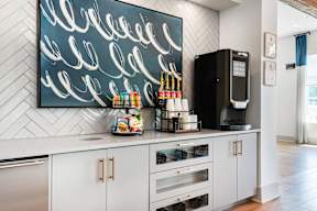 A modern kitchen with a large painting on the wall and a coffee machine on the counter.