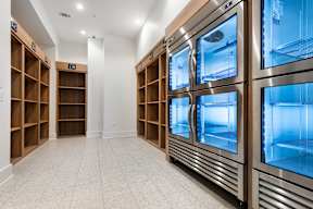 A row of stainless steel ovens are lined up in a clean, empty kitchen.