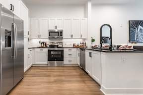 A modern kitchen with white cabinets and stainless steel appliances.