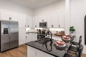 A modern kitchen with a black countertop and stainless steel appliances.