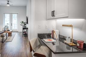 A kitchen with a black countertop and a wooden floor.