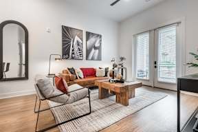 A living room with a grey sofa, a wooden coffee table, and a large mirror on the wall.