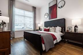 A bedroom with a large bed and a wooden dresser.
