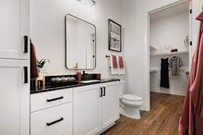 A bathroom with a white toilet and a white cabinet with a mirror above it.