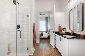 A bathroom with a glass shower stall and a wooden floor.