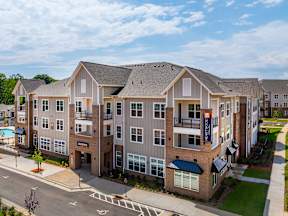A large apartment complex with a pool and a clear sky.