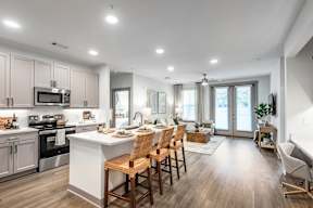 A modern kitchen with wooden floors and a white island.