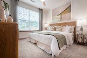 A bedroom with a large bed and a painting on the wall.