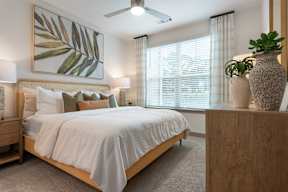 A bedroom with a large bed and a painting on the wall.