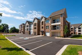 A large, modern apartment complex with a parking lot in front.