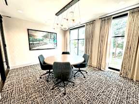 A conference room with a table, chairs, and a painting on the wall.