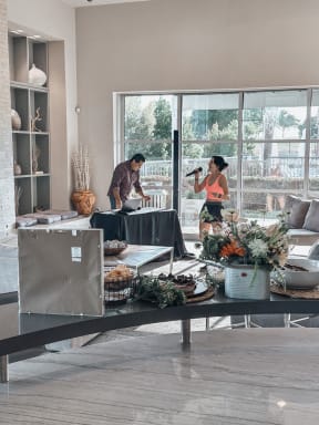 a man and woman standing in a living room with a table with food on it