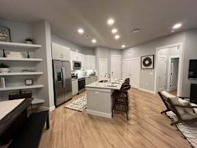 A modern kitchen with wooden floors and stainless steel appliances.