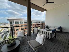 A balcony with a table, chairs, and a potted plant.