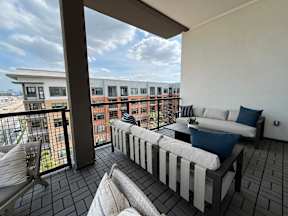 A balcony with a white couch and a black and white striped pillow.