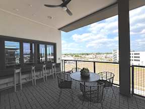 A balcony with a table and chairs overlooking a cityscape.