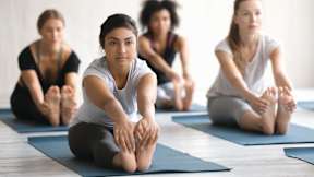 A group of people are sitting on yoga mats in a room.