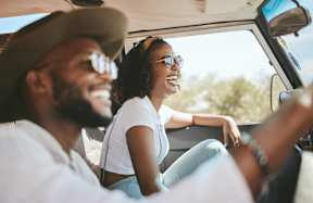 a man and woman sitting in a car and laughing