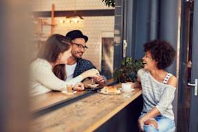 Three people are sitting at a table in a cafe.