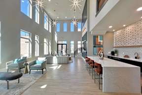 A spacious living room with a long white marble counter and a row of chairs.
