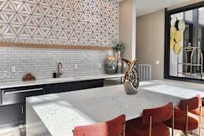 A modern kitchen with a marble countertop and a patterned backsplash.