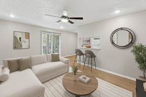 A living room with a white couch, a round table, and a ceiling fan.