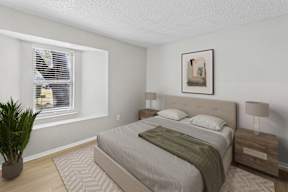 A bedroom with a large bed, a potted plant, and a framed picture on the wall.