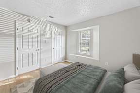 A bedroom with a bed, two closets, and a window.