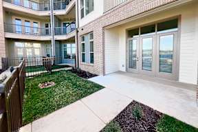A view of a courtyard with a grass patch and a small garden.
