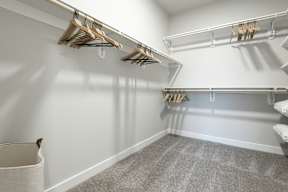 A walk-in closet with white walls and grey carpet.
