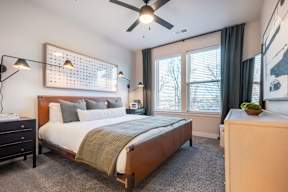 A bedroom with a bed, nightstand, and a ceiling fan.