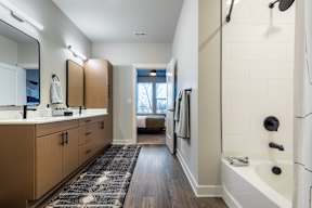 A bathroom with a white tub and wooden cabinets.