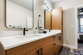 A bathroom with a sink, mirror, and wooden cabinets.