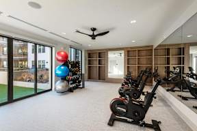 A room with a row of stationary bikes and a red ball.