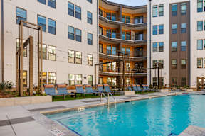 A large swimming pool in front of a modern apartment building.