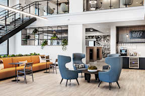 A modern living room with a staircase and a kitchen area.