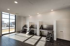 A large empty room with a kitchenette and stairs leading to an upper level.